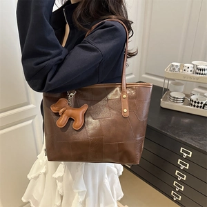 Brown patchwork leather tote bag with a dog charm shown in a cozy indoor lifestyle setting