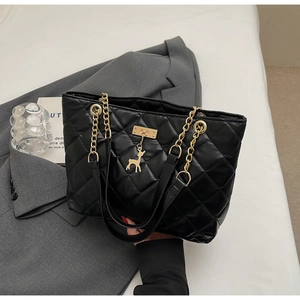 Close-up of black quilted tote bag with golden chain handle and small deer pendant