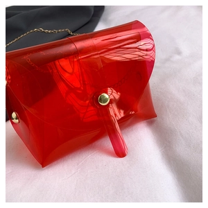 Détail du petit sac transparent rouge en PVC avec chaîne dorée et fermoir rond
