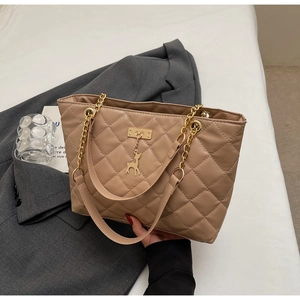 Detail of quilted tote bag with golden chain straps and small deer pendant charm