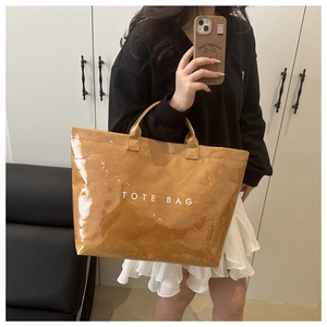 Detailed macro view of brown glossy tote bag with vintage paper texture and white text