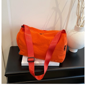 Détail du sac cylindrique en nylon orange vif avec broderie FY et bandoulière réglable
