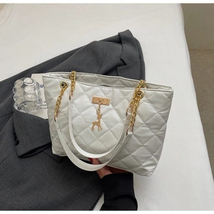 Close-up of white quilted tote bag featuring gold chain handle and deer charm detail