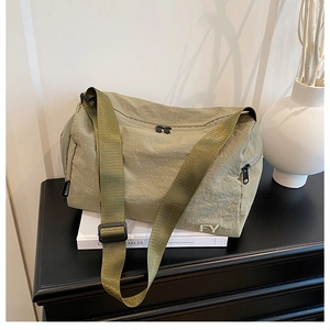 Détail du sac messager en nylon vert olive avec double fermeture éclair et logo argenté