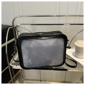 Détail de la sacoche bandoulière en maille noire et blanche sur une étagère en métal