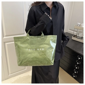 Detail of green oversized tote bag with wrinkled texture and white TOTE BAG text print