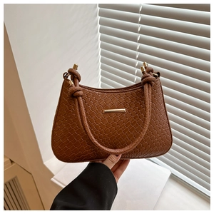 Detail of brown woven textured hobo bag with gold metal trim and knotted strap