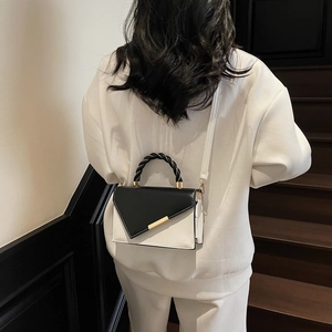 Minimalist black and white patchwork handbag with gold metal bar and woven handle