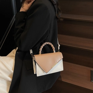 Minimalist colorblock square crossbody bag with woven handle shown in elegant office setting