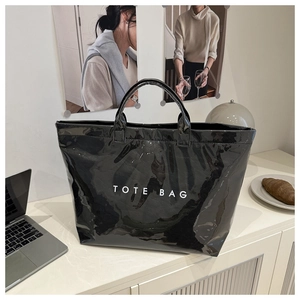 Macro shot of glossy black patent leather material and white TOTE BAG lettering detail