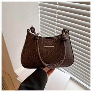 Detail of dark brown woven shoulder bag with knotted strap and gold metallic trim
