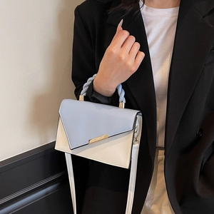 Chic two-tone crossbody bag with light blue woven handle and gold geometric buckle