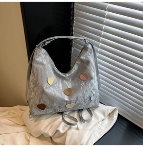 Close-up of metallic silver tote bag with colorful leather heart patches and wrinkled texture