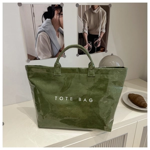 Detail of avocado green tote bag with white text and natural wrinkled texture surface