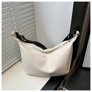Gros plan du sac fourre-tout en similicuir crème avec lettrage doré et détails métalliques