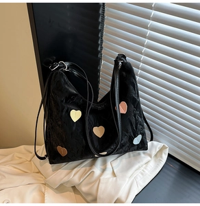 Detail of black pleated fabric tote with colorful heart patches and thin leather straps