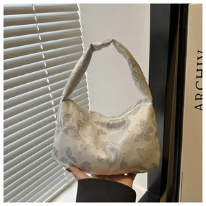 Détail du sac à main en soie blanche avec motif papillon argenté et poignée rembourrée