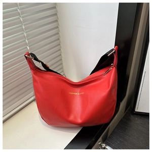 Gros plan sur le sac besace rouge en similicuir avec logo doré et bandoulière en tissu
