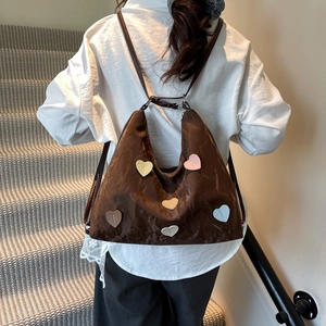 Brown tote bag with colorful heart patches shown from a back view on a model