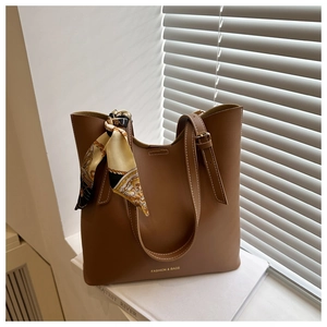 Détail d'un sac cabas marron avec surpiqûres blanches contrastées et un foulard en soie décoratif