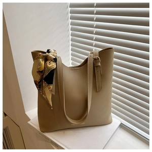 Détail du sac fourre-tout kaki avec foulard et boucles métalliques à la lumière naturelle