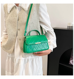 Détail d'un sac bandoulière matelassé vert avec fermoir doré et bandoulière réglable