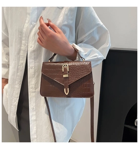 Détail du sac bandoulière marron foncé motif crocodile avec fermoir doré sur modèle