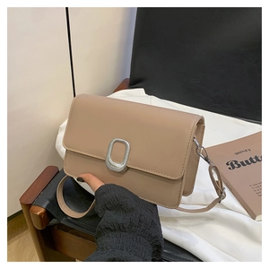 Close-up of beige PU leather square bag with silver oval metal buckle and long shoulder strap