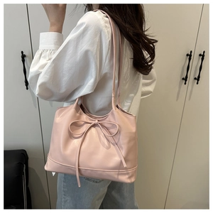Detail view of pink tote bag with large bow drawstring on a model in a minimalist room