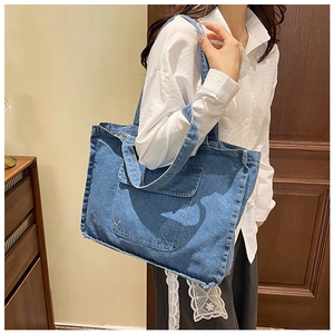 Detail der blauen gewaschenen Denim-Tragetasche mit großer Vordertasche und Trageriemen