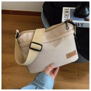 Detail of beige nylon shoulder bag with adjustable wide strap and circular fashion logo patch