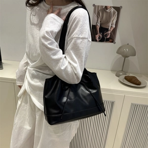 Elegant black PU leather tote bag with drawstring detail on a minimalist model shoulder