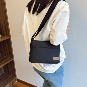 Minimalist black nylon crossbody bag with adjustable strap and fashion leather patch
