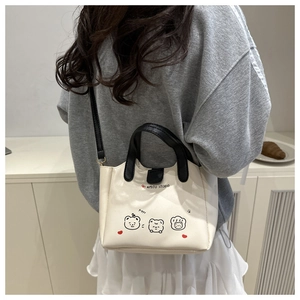 Détail d'un sac à main blanc contrasté avec motifs de chiots mignons et bandoulière noire