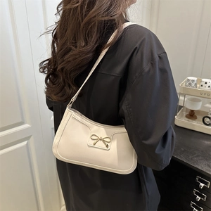 Chic cream white baguette shoulder bag with a delicate gold bow accent for women
