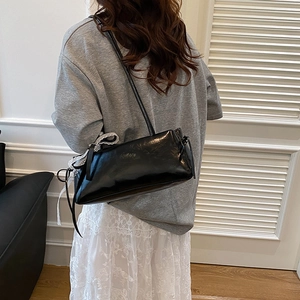Stylish black patent leather underarm bag with white lace bows and slim shoulder strap