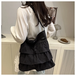 Modern black ruffle tote bag styled on model in a minimalist home setting