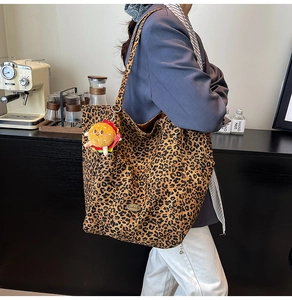 Dettaglio della borsa tote leopardata con ciondolo a forma di hamburger di peluche in un caffè