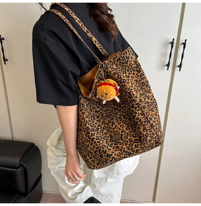 Dettaglio borsa shopper in tela leopardata con fodera marrone e ciondolo a hamburger