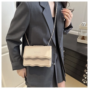 Close-up of cream leather crossbody bag featuring wavy pleated edges and chain strap