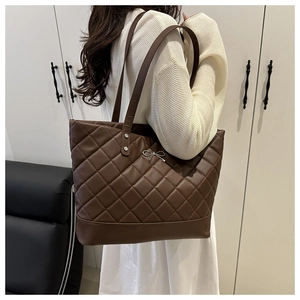 Detail of the dark brown quilted tote bag with silver bow accent and metal studs