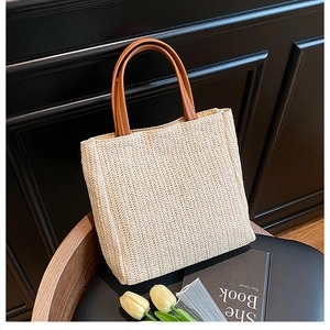 Detail of hand-woven straw bag with premium brown handles and v-shaped texture
