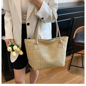 Dettaglio della trama della borsa tote in paglia intrecciata e manico beige sulla borsa a tracolla