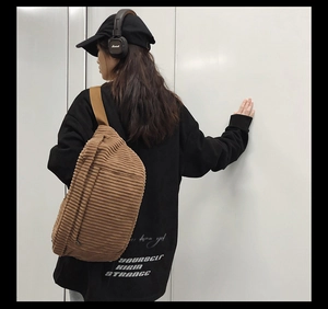 Détail de la texture du sac bandoulière en velours côtelé marron porté par un mannequin
