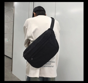 Gros plan sur la texture du sac bandoulière en velours côtelé noir porté par un mannequin