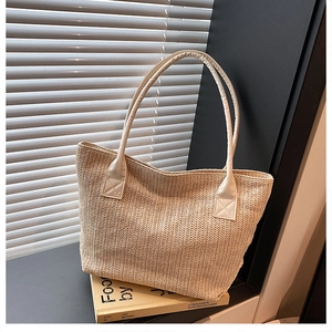 Detailed close-up showing the intricate texture of the beige straw woven tote bag