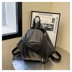 Close-up of black synthetic leather backpack with U-shaped zipper pocket on a metal table