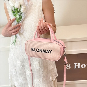 Pink woven cylindrical pillow bag with silver zipper and leather shoulder strap