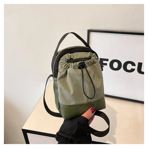 Detail view of army green nylon drawstring bag with leather base and woven shoulder strap