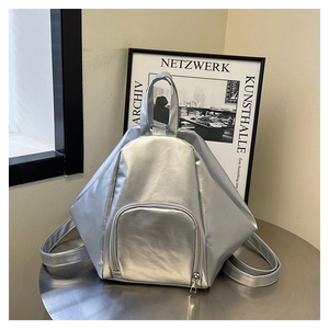 Detail of silver geometric backpack with textured metallic panels and a top handle